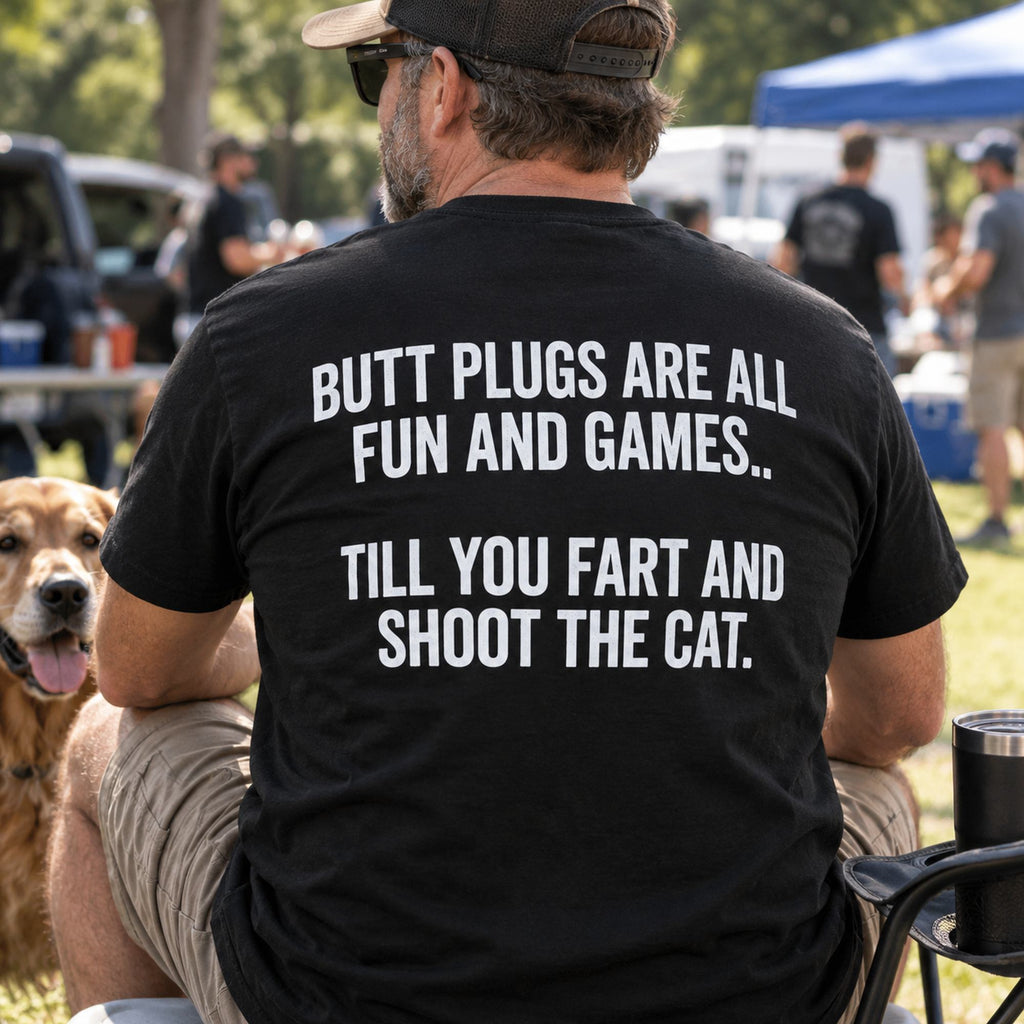 Butt Plugs Are All Fun And Games black back-print graphic tee on a seated male model outdoors