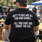 Butt Plugs Are All Fun And Games black back-print graphic tee on a seated male model outdoors