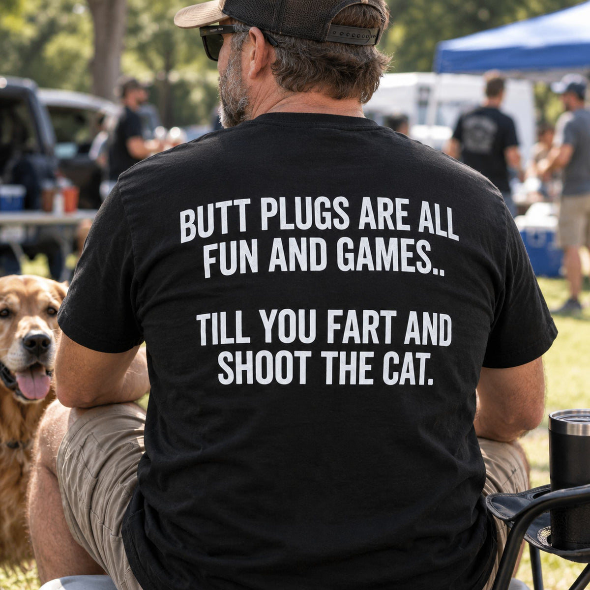 Butt Plugs Are All Fun And Games black back-print graphic tee on a seated male model outdoors