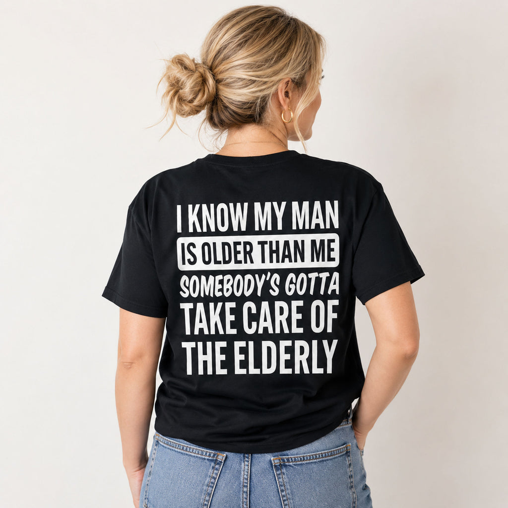 I Know My Man Is Older Than Me funny back-print graphic tee on a woman in black, rear view