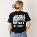 I Know My Man Is Older Than Me funny back-print graphic tee on a woman in black, rear view