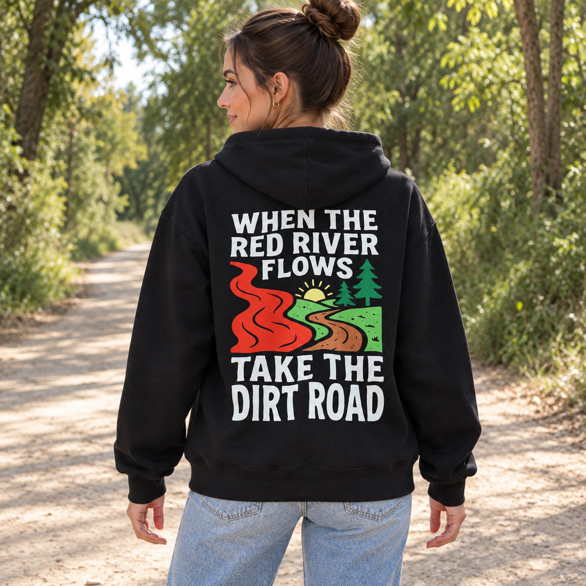 When The Red River Flows Take The Dirt Road black hoodie back print woman on a wooded path
