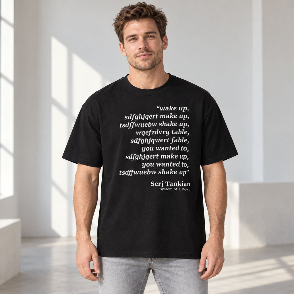 Black tee front on an adult male model with Wake Up scrambled text and Serj Tankian attribution