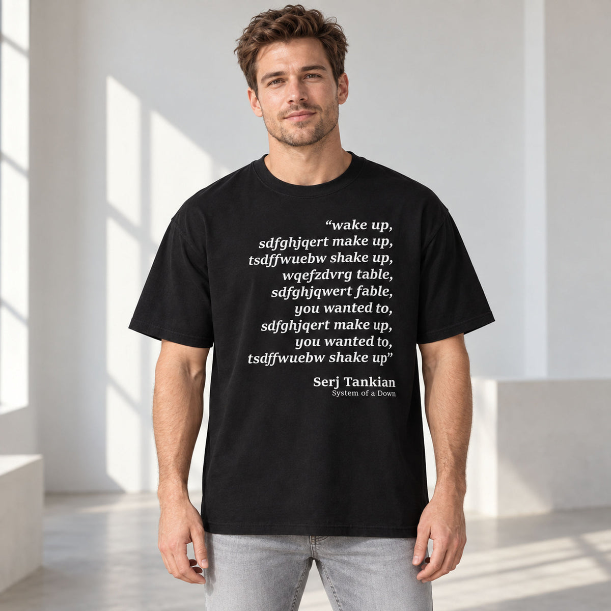 Black tee front on an adult male model with Wake Up scrambled text and Serj Tankian attribution