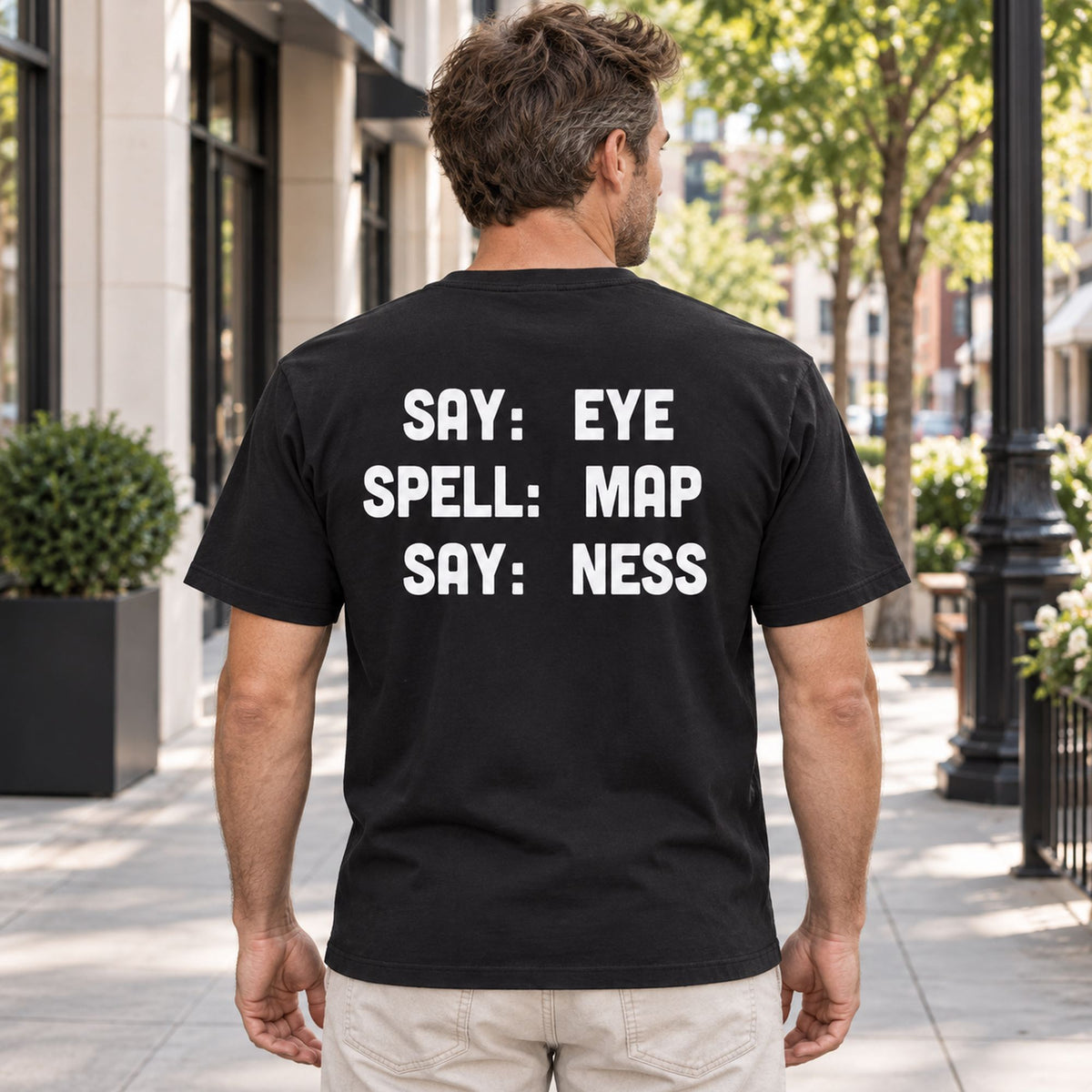 Say Eye Spell Map Say Ness funny three-line back print black T-shirt male model on a city sidewalk