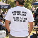 Butt Plugs Are All Fun And Games white back-print graphic tee on a standing male model at an outdoor gathering