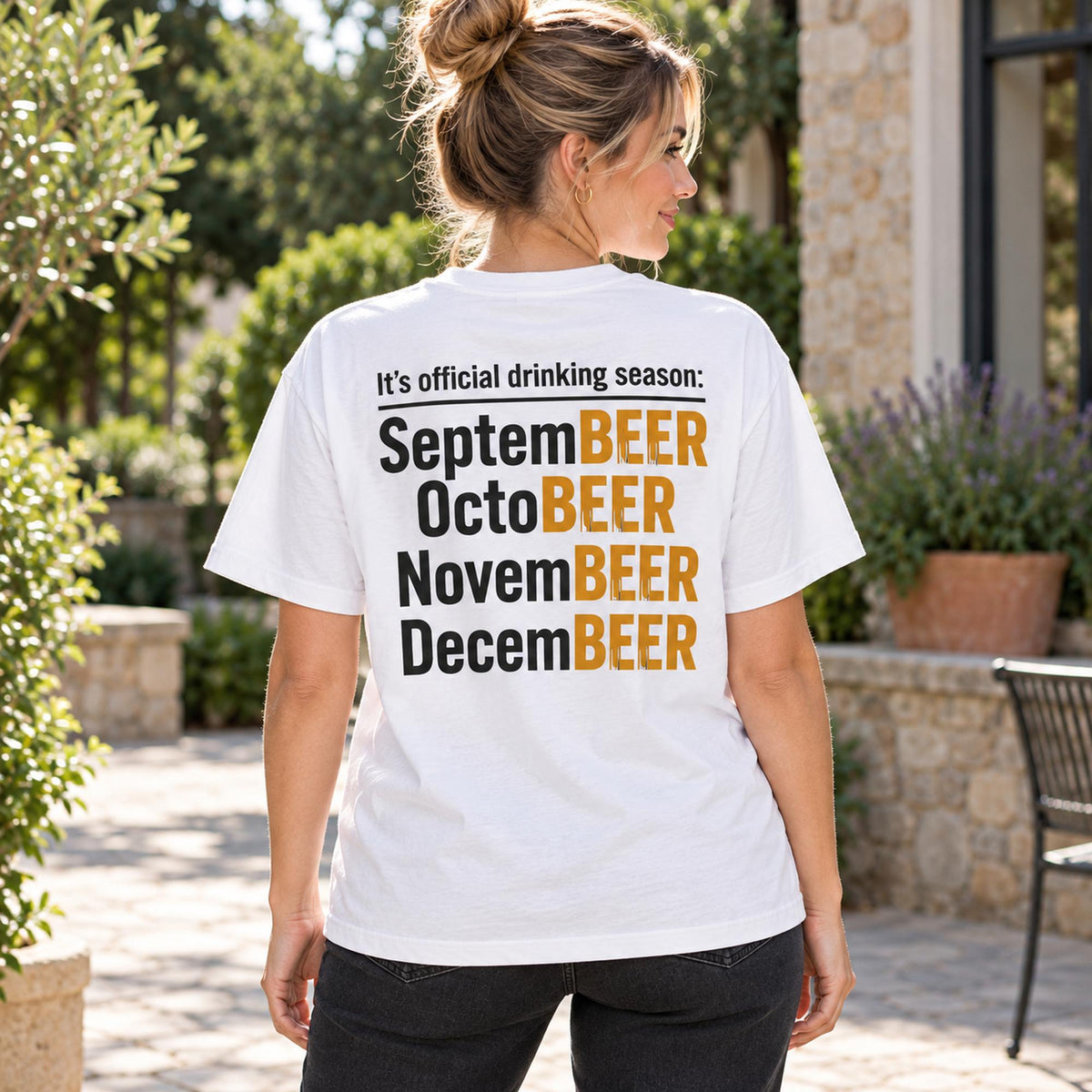 Official Drinking Season beer-month wordplay on white T-shirt back, adult female model outdoors