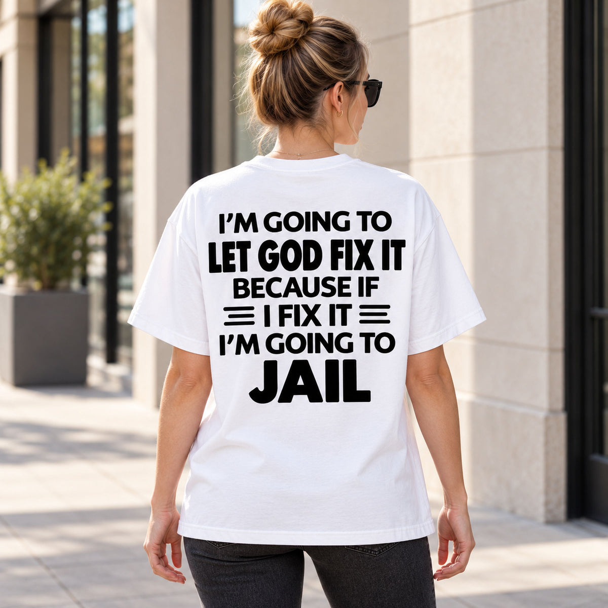 Let God Fix It funny jail punchline on white T-shirt back, adult female model outdoors