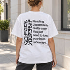 White T-shirt back on a female model showing the same sideways-reading joke and angular lettering