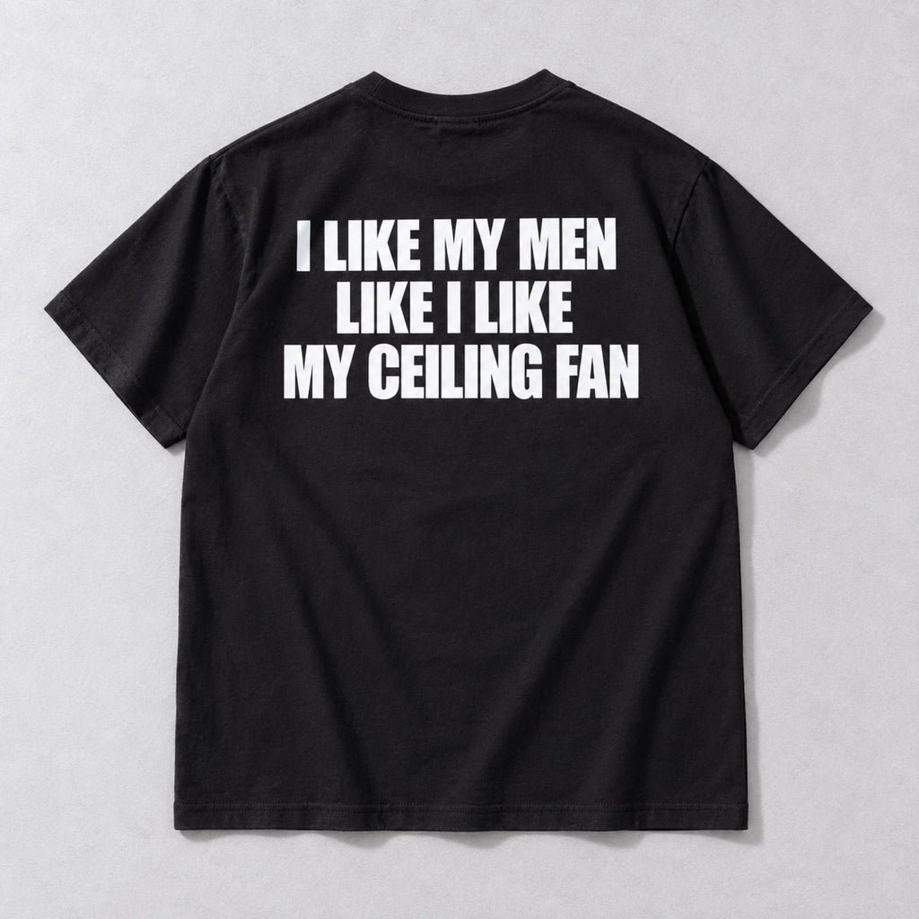 I Like My Men Like I Like My Ceiling Fan black tee back flat lay with white three-line slogan