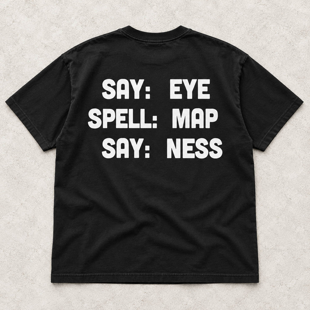 Say Eye Spell Map Say Ness white lettering on a black T-shirt back flat lay on a textured surface