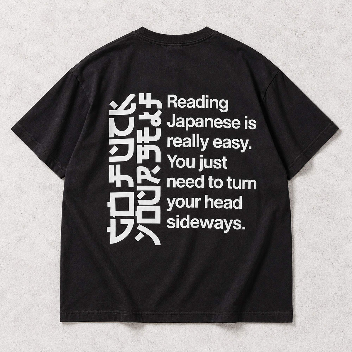 Black T-shirt back flat lay with the complete Reading Japanese Is Really Easy sideways-reading print