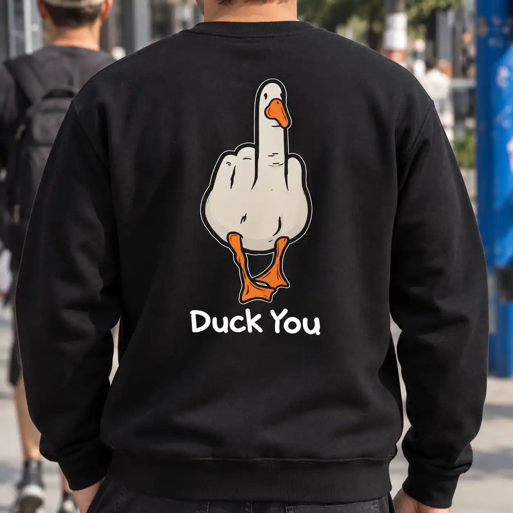 Duck You black sweatshirt worn on a city sidewalk, displaying the cartoon duck back print