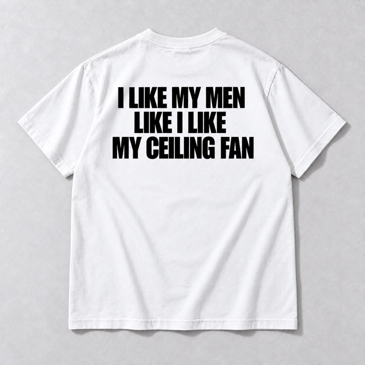 I Like My Men Like I Like My Ceiling Fan white tee back flat lay with black three-line slogan
