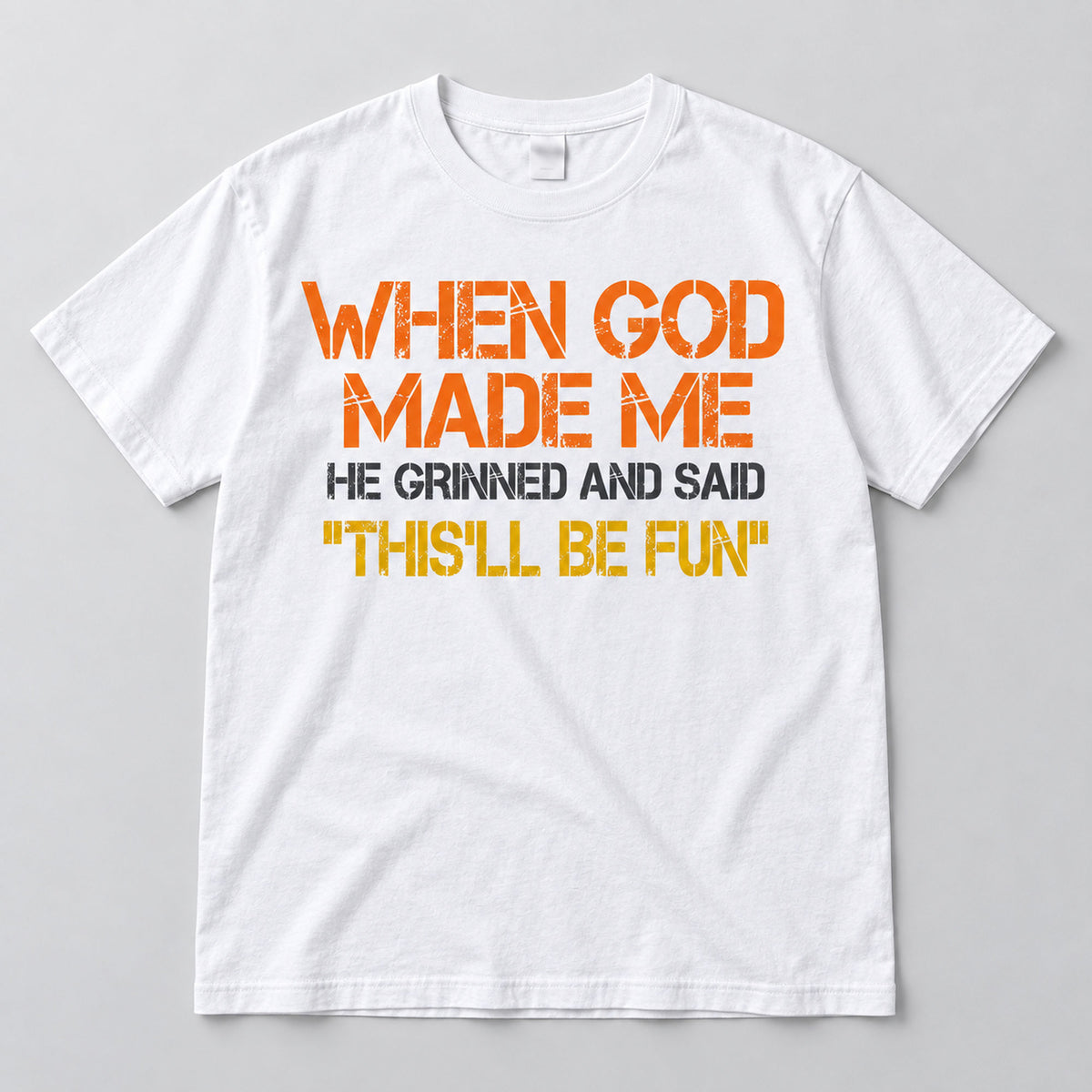 White This'll Be Fun graphic T-shirt laid flat from the front with the When God Made Me slogan in warm colors and charcoal