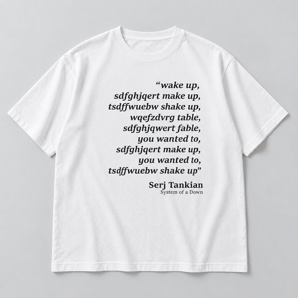 White tee front flat lay with Wake Up scrambled text and Serj Tankian attribution