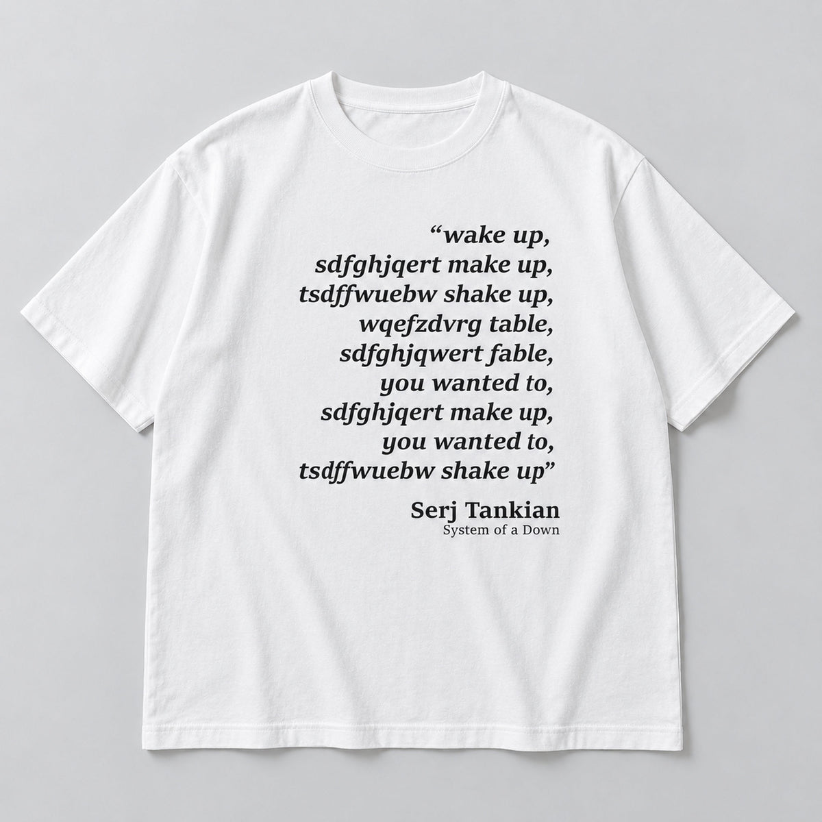 White tee front flat lay with Wake Up scrambled text and Serj Tankian attribution