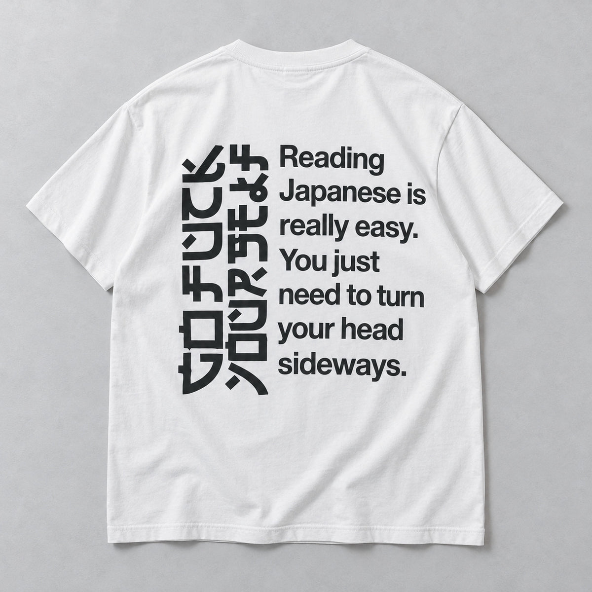 White T-shirt back flat lay with black angular artwork and the complete sideways-reading joke
