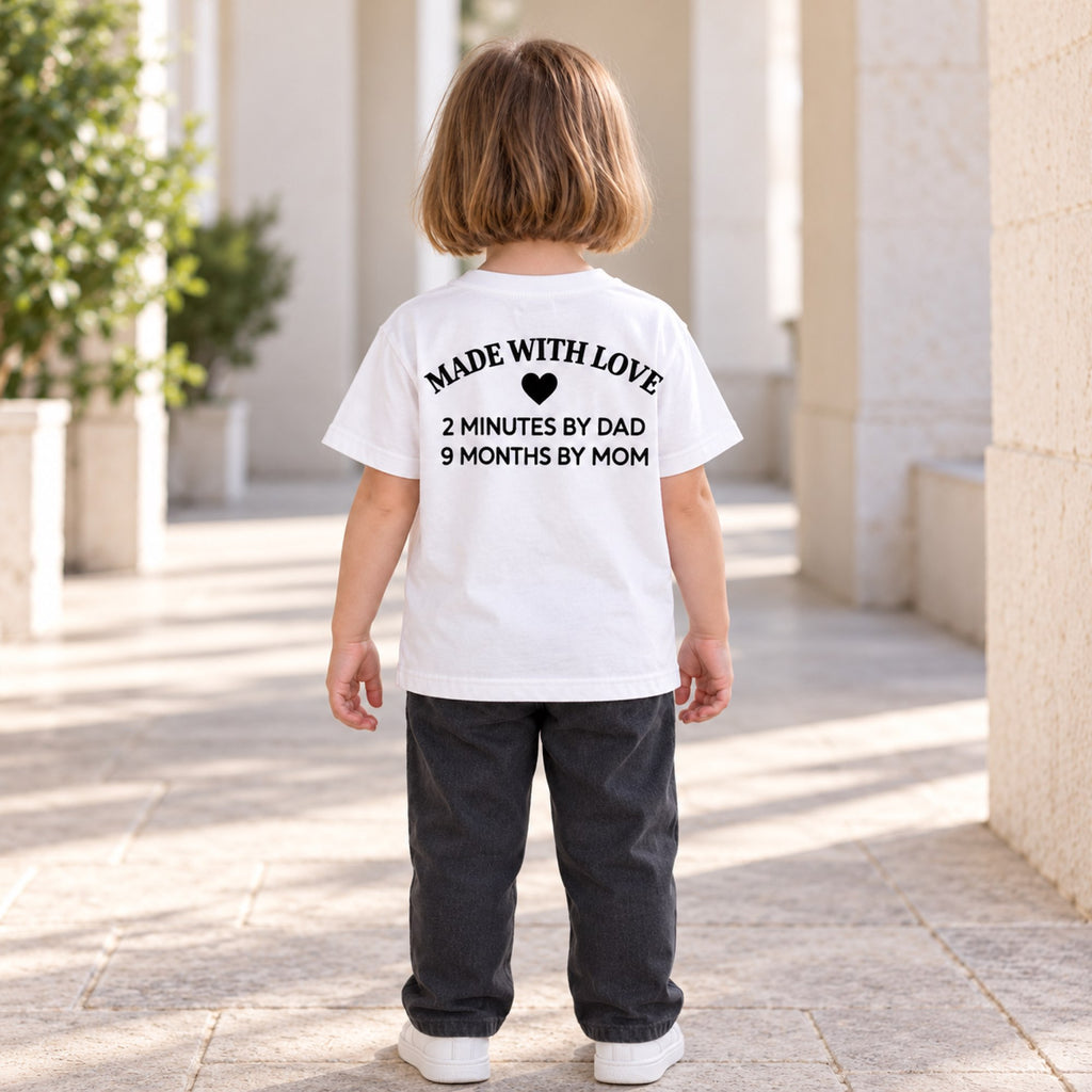 Made With Love kids white T-shirt with black family joke back print on a child outdoors