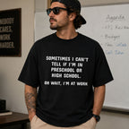 Black funny work graphic tee with white preschool-or-high-school slogan on male model in office