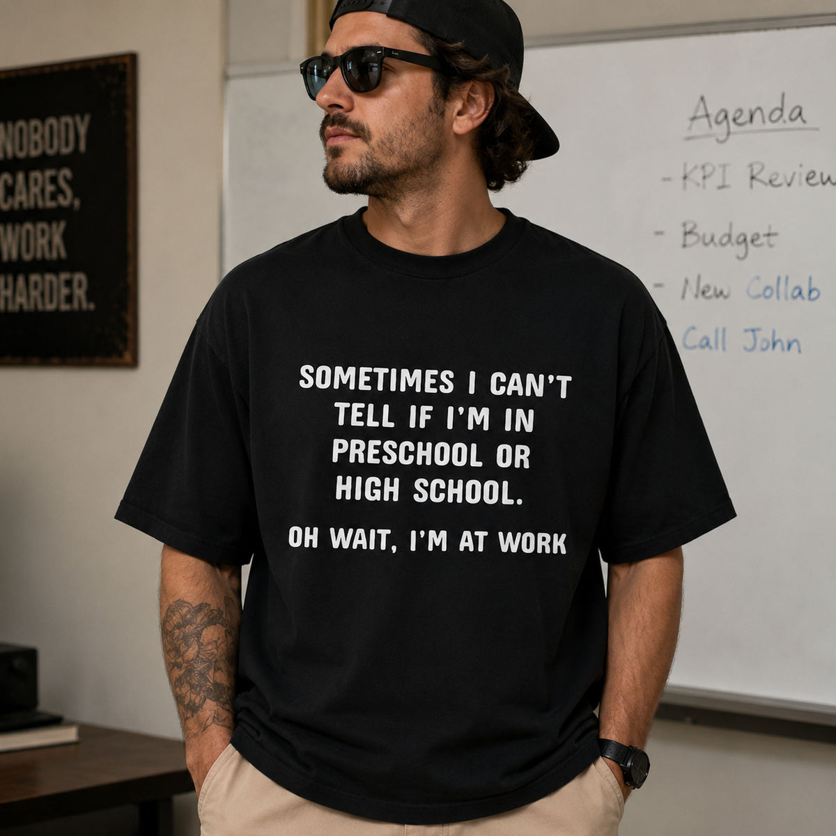 Black funny work graphic tee with white preschool-or-high-school slogan on male model in office