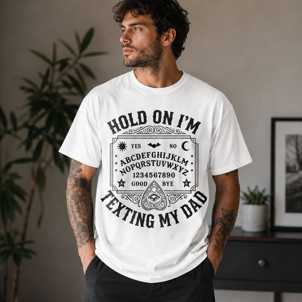 Male model wearing white Hold On I'm Texting My Dad Ouija board graphic tee, front view