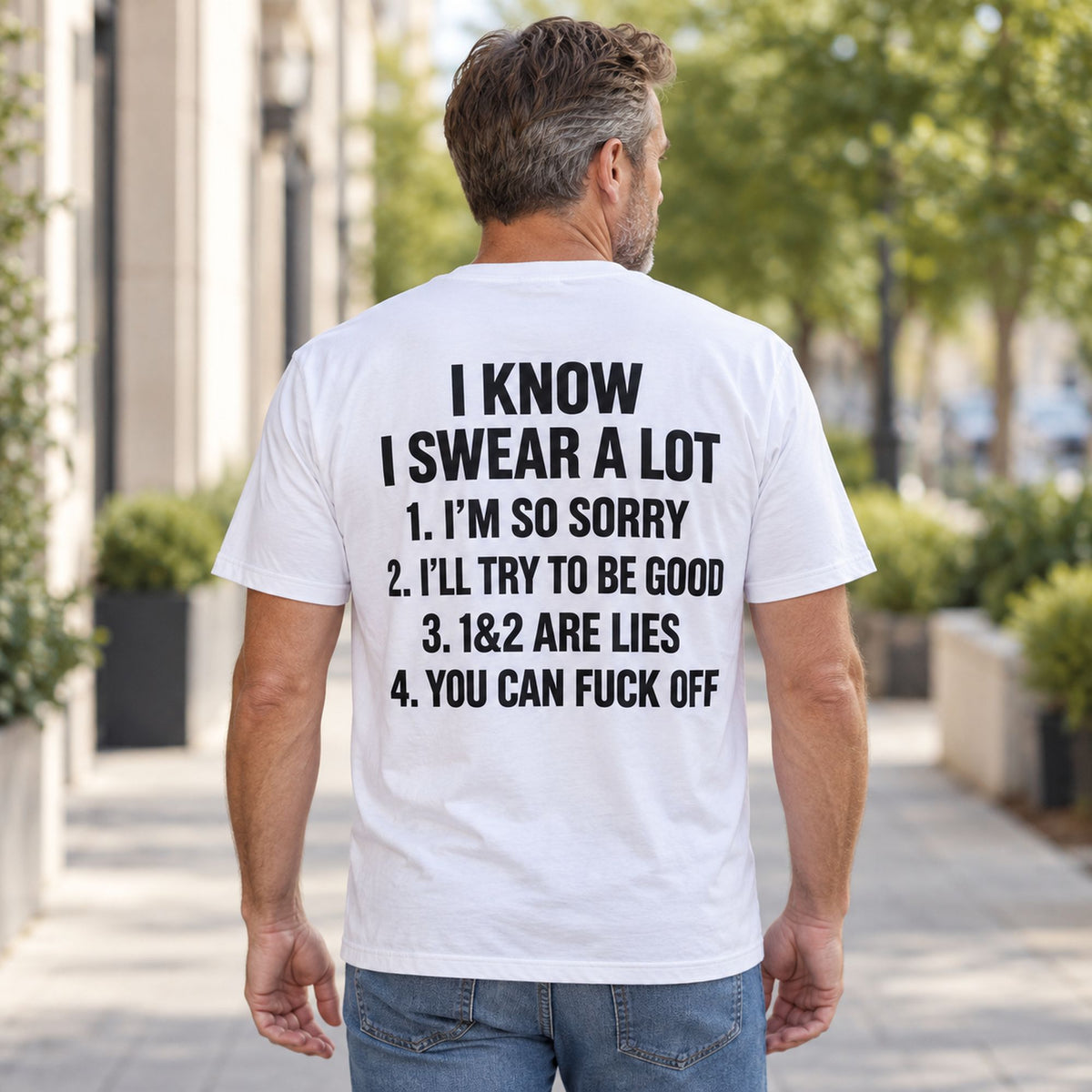 White I Know I Swear A Lot sarcastic graphic tee with black six-line back print, rear view on a male model outdoors