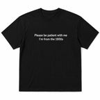 Black Please Be Patient I'm From the 1900s funny front-print graphic tee flat lay on a white background
