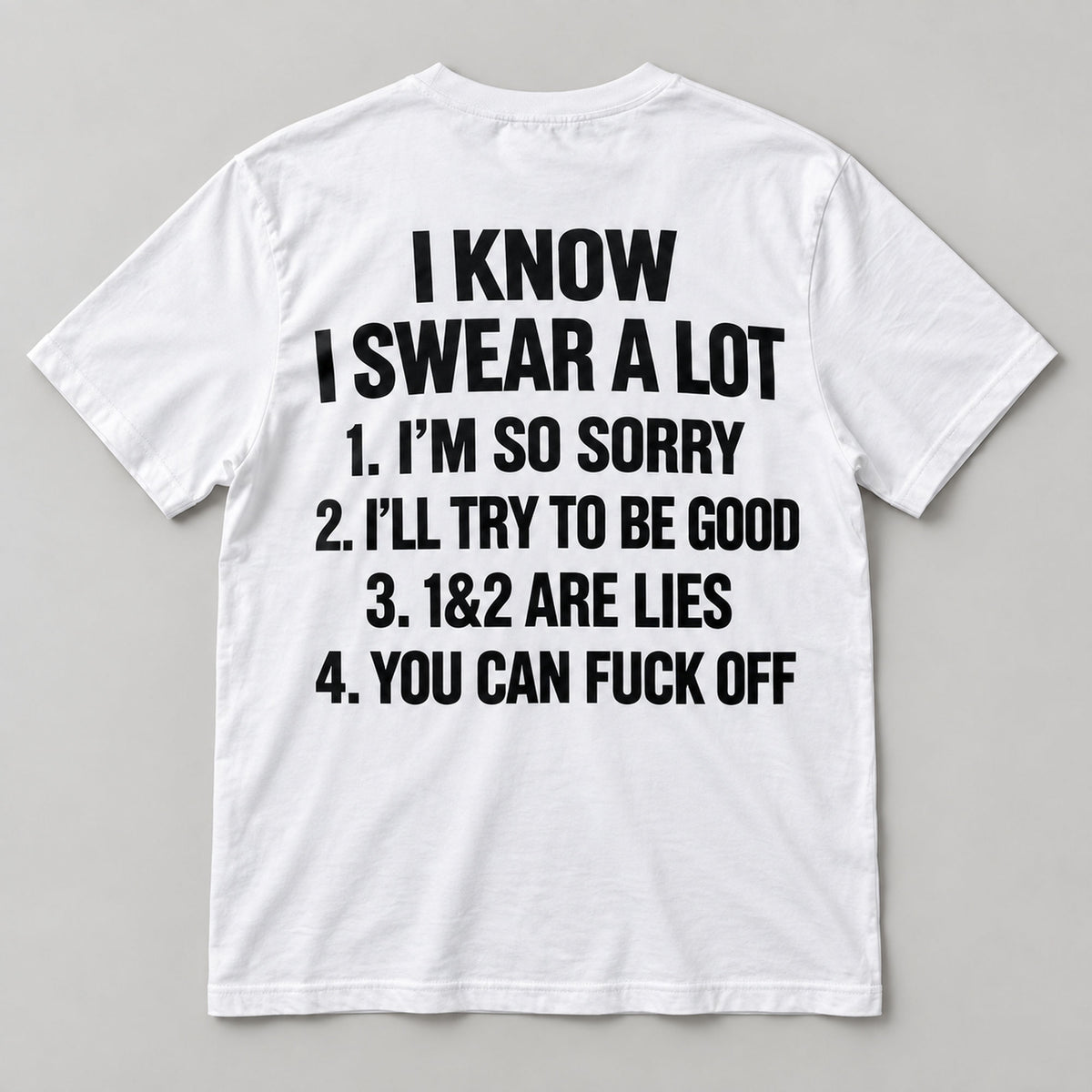 White I Know I Swear A Lot funny graphic T-shirt back flat lay with black lettering on a light grey background